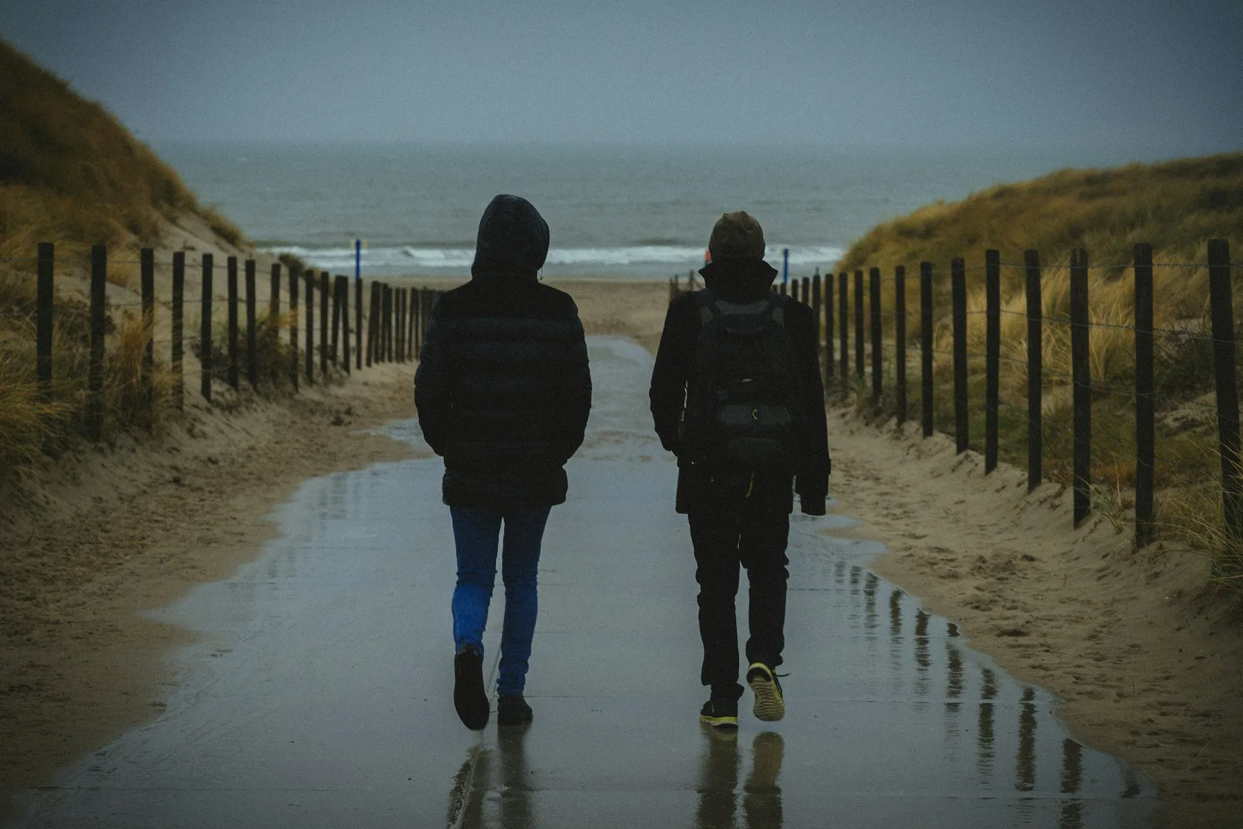 Pareja paseando de espaldas por un camino junto al mar