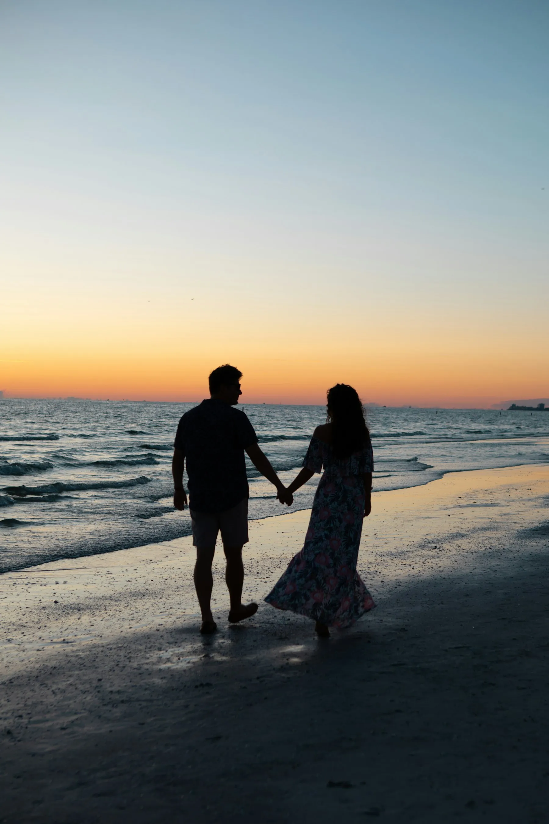 Silueta de una pareja paseando por la orilla al atardecer
